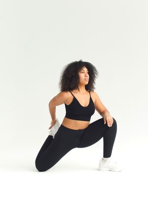 woman in black workout clothing stretch and opening up hips.