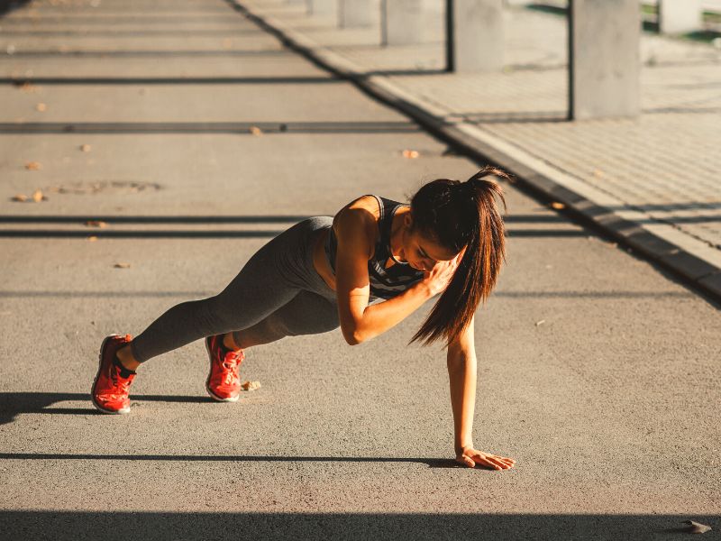 woman doing shoulder taps with holing a plank position.